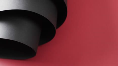 close up of rolls of black paper and copy space on red background