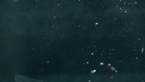 a red tomato falls into the water and flies under the water with bubbles.