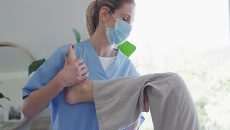 una trabajadora de la salud estirando la pierna de una mujer mayor en casa