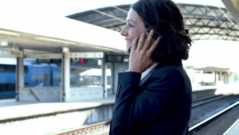 mujer de negocios con teléfono móvil en la estación de tren