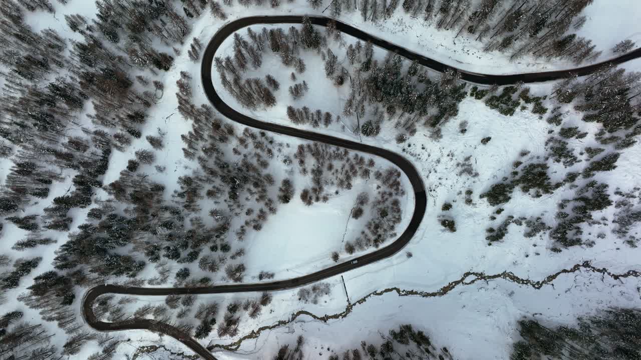 vista aérea cenital de drones de una calle estrecha en las montañas entre el bosque con nieve en invierno
