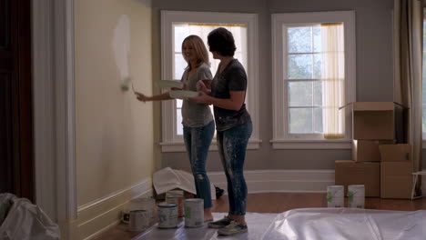 two women painting a wall in a room
