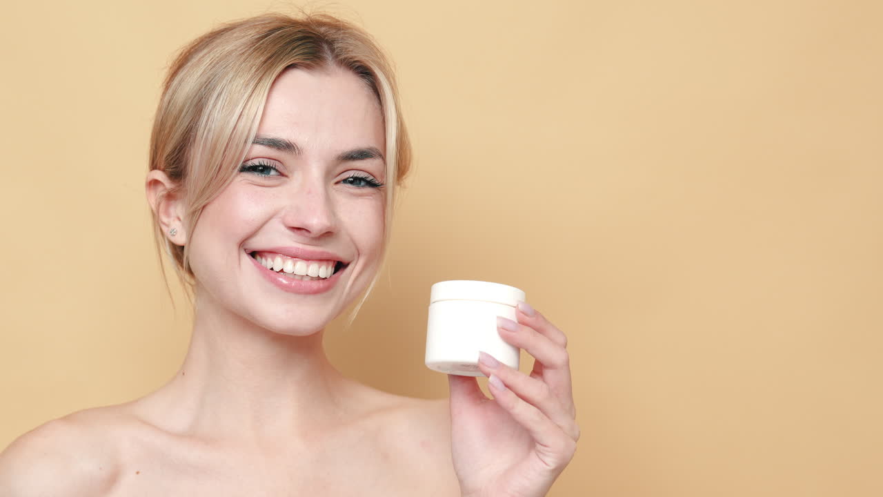 mujer feliz sosteniendo crema para el cuidado de la piel