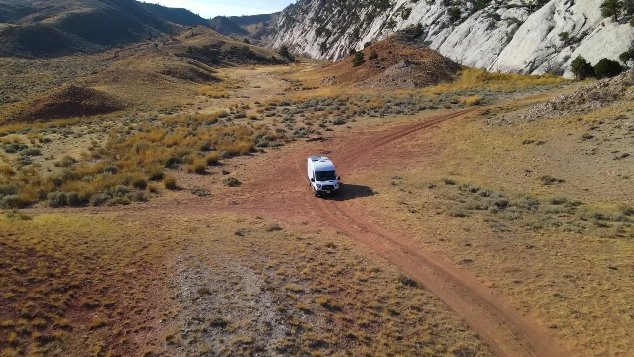 alejarse de una camioneta que sale de un espacio árido y acantilados rocosos