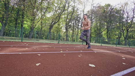 shirtless runner training on the stadium. strong athlete is running in the park at sunny day. healthy lifestyle. slow motion.
