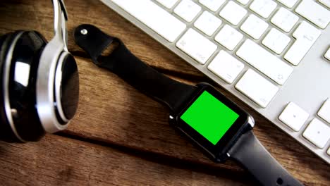 headphones, smartwatch and keyboard on wooden table 4k