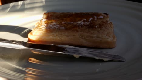 person pouring honey on cooked crumpet and spreading with butter knife in kitchen