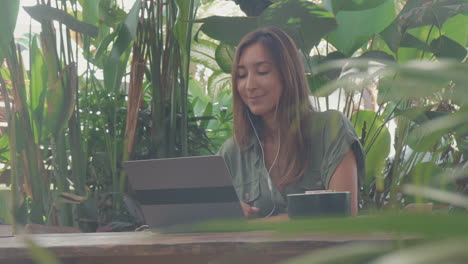 woman using laptop among greens