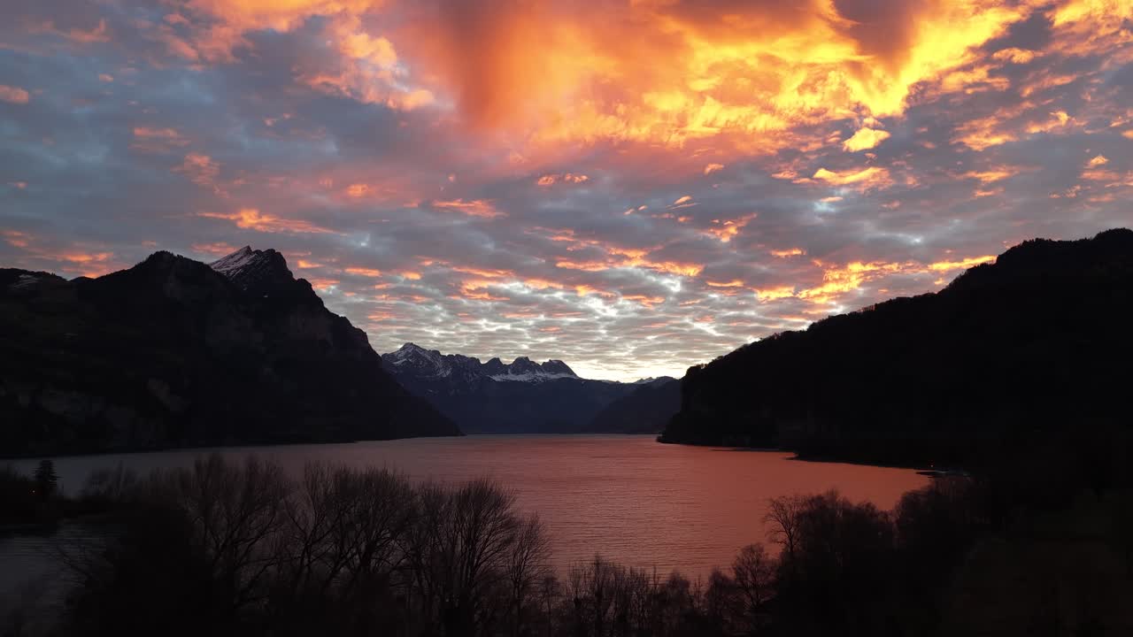 Mountain lake with snow peaks and clouds at sunset in Switzerland Alps