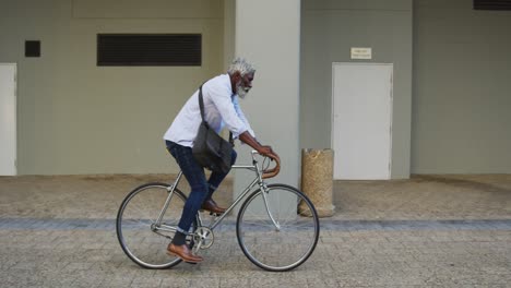Afroamerikanischer-älterer-Mann,-Der-Im-Firmenpark-Fahrrad-Fährt