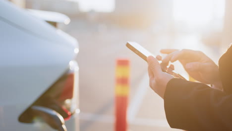 mujer cargando un coche eléctrico con un teléfono inteligente