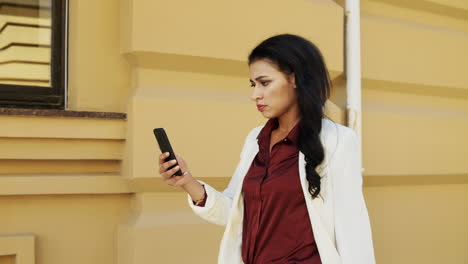 Mixed-race-woman-having-video-call-outside.-Young-businesswoman-walking-outdoors