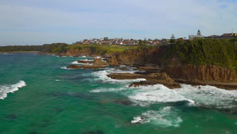 aerial pullback view of sea stacks with splashing waves at cathedral rocks near coastal town in kiama downs, nsw australia