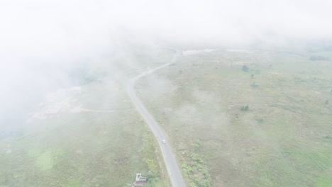 Top-view-across-clouds-over-rural-area-with-lush-vegetation-after-heavy-rains-up-to-mountains