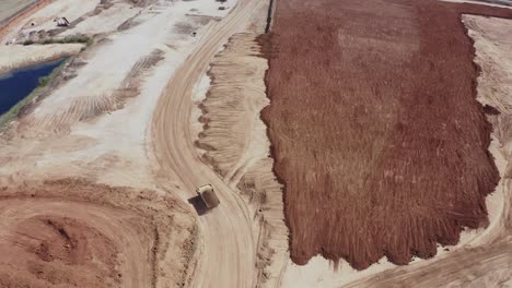 a large truck loaded with sand is heading towards the construction site, aerial shots of the truck alongside the construction site and materials