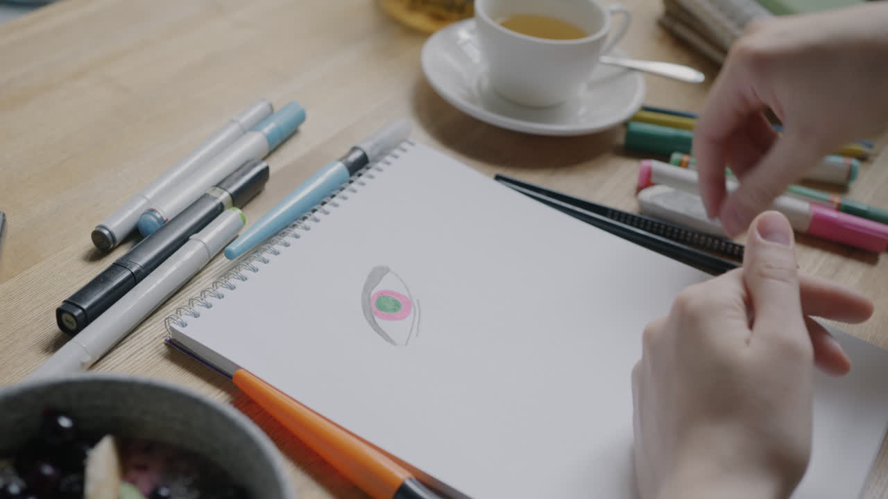 Person drawing an eye on a notebook in a cafe