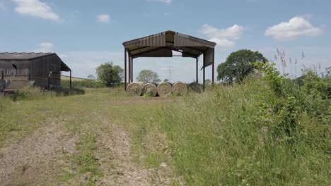 Große-Runde-Heuballen-Werden-Unter-Einem-Scheunendach-Aufbewahrt,-Um-Sie-Bei-Nassem-Wetter-Trocken-Zu-Halten