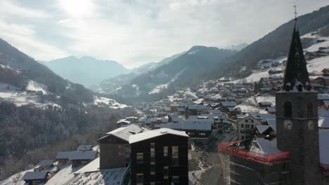 Cinematic-aerial-of-a-beautiful-church-in-an-idyllic-Swiss-village-in-winter