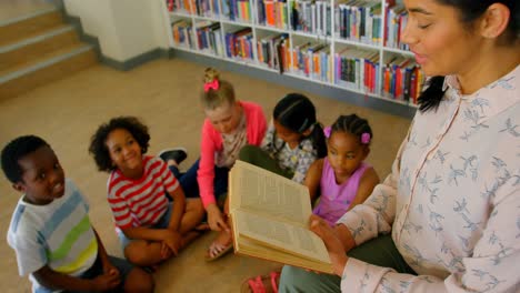 maestra asiática que enseña a los escolares en la biblioteca de la escuela 4k