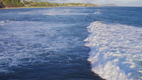 drone-footage-moving-along-with-the-white-capped-blue-ocean-waves-along-the-coast-of-Oahu-Hawaii-as-the-sea-foam-gathers-near-the-coast