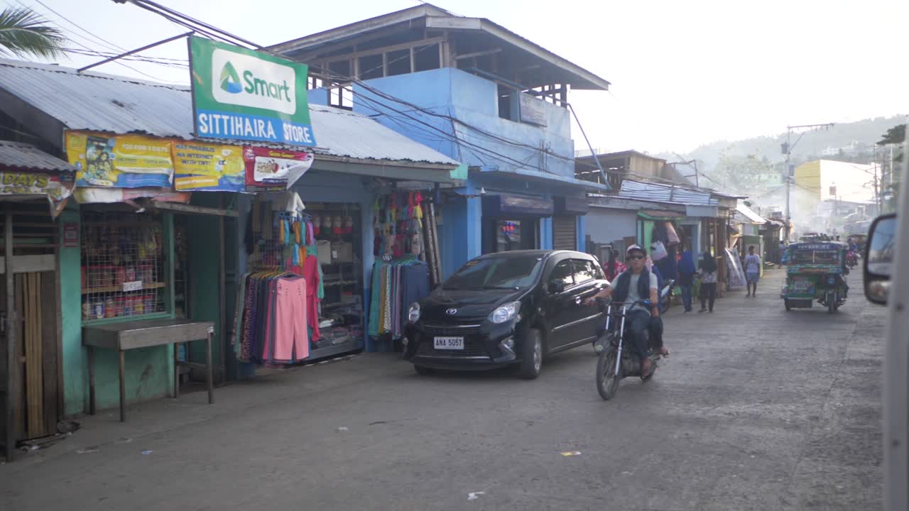 Traffic and people on a crowded city street in the Philippines. Slow motion view of cycle taxis called tuk tuks carrying passengers and ready to give rides. Busy Asian street scene.