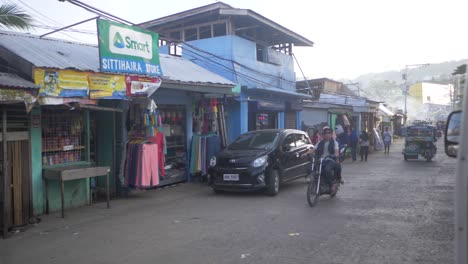 traffic and people on a crowded city street in the philippines. slow motion view of cycle taxis called tuk tuks carrying passengers and ready to give rides. busy asian street scene.