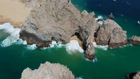 Filmische-Drohnenaufnahme-Von-Wellen,-Die-Auf-Meeresklippen-Krachen,-Mit-Playa-Del-Amor-Und-El-Arco-Im-Blick-In-Cabo-San-Lucas,-Mexiko