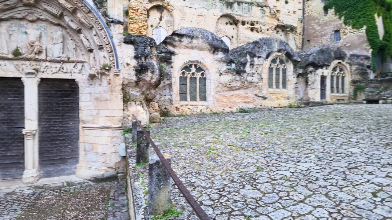 Een langzame pan-opname onthult de kalkstenen gevel en houten deuren van een middeleeuwse kerk.