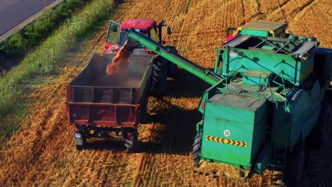 Combine-Harvester-Loading-Truck-With-Harvested-Grain---drone-shot