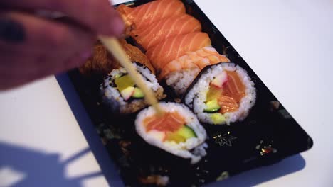 chopsticks attempt to pick up dragon sushi roll on narrow focus plate