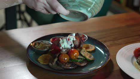 chef pouring creamy white sauce on delicious meat plate in restaurant