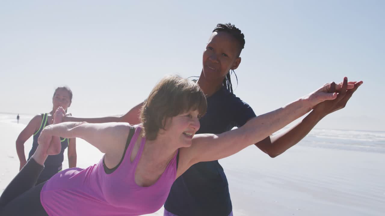 profesora de yoga afroamericana mujer ayudando a una mujer en la playa y fondo de cielo azul