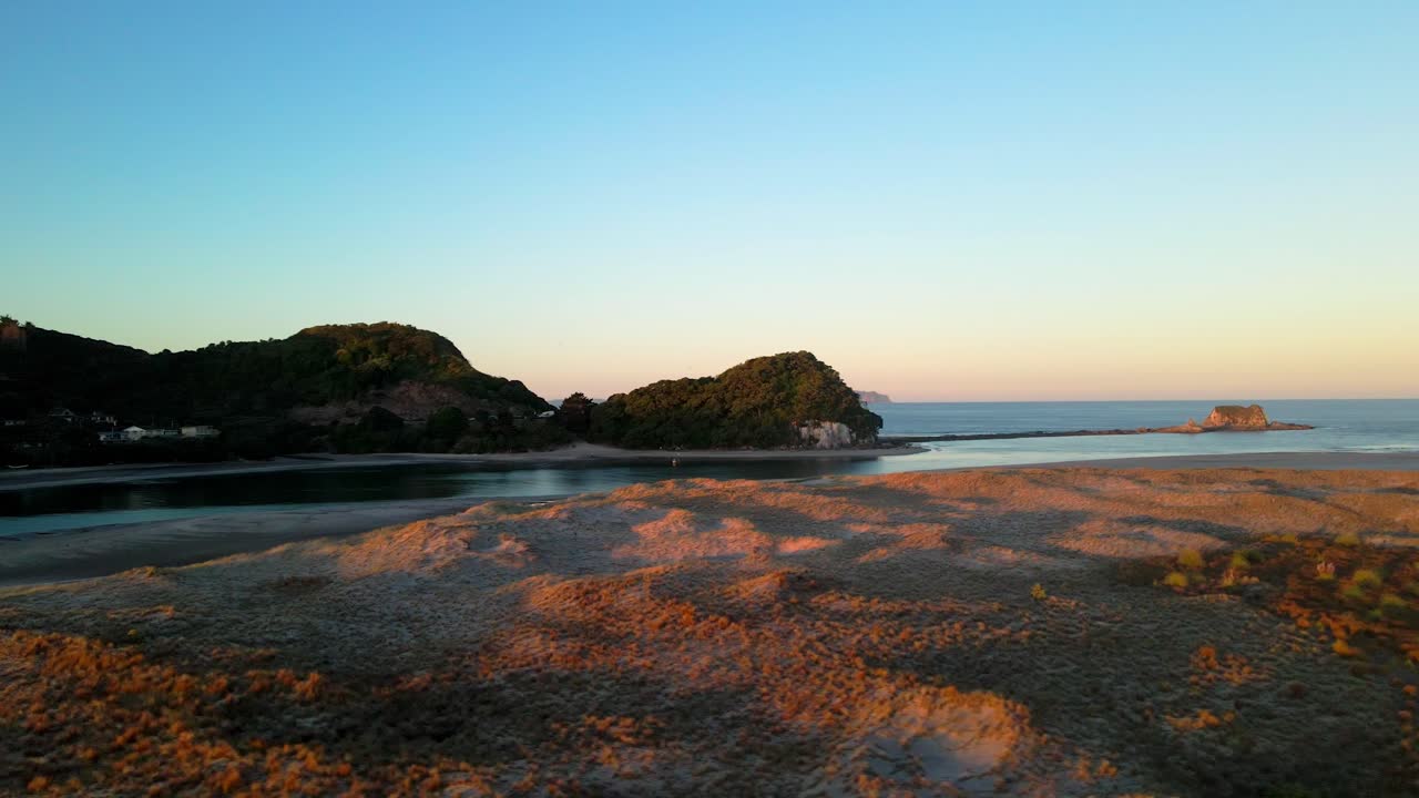 toma de seguimiento aérea baja de famosas cabezas de mangawhai durante la puesta de sol en nueva zelanda.