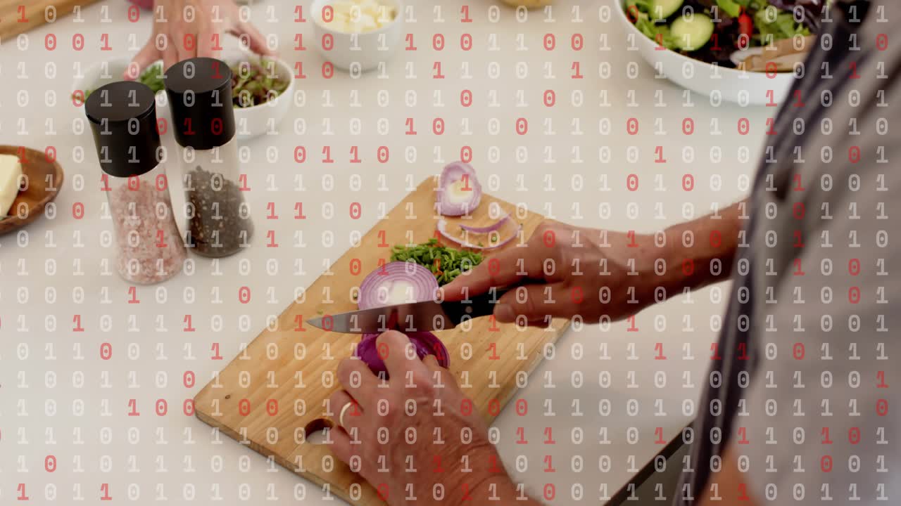 Lead cook demonstrating pepper while foreground cook slicing onion for shared salad, tablet guiding