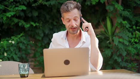 Businessman-drinking-beverage-and-talking-on-cellphone-in-street-restaurant