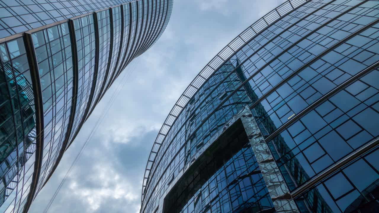 rascacielos timelapse, fachadas de edificios de oficinas altos, cielo azul y nubes que se mueven rápidamente en el time-lapse reflejado en el vidrio de la superficie de las ventanas. time lapse centro del distrito financiero, fondo de la ciudad moderna
