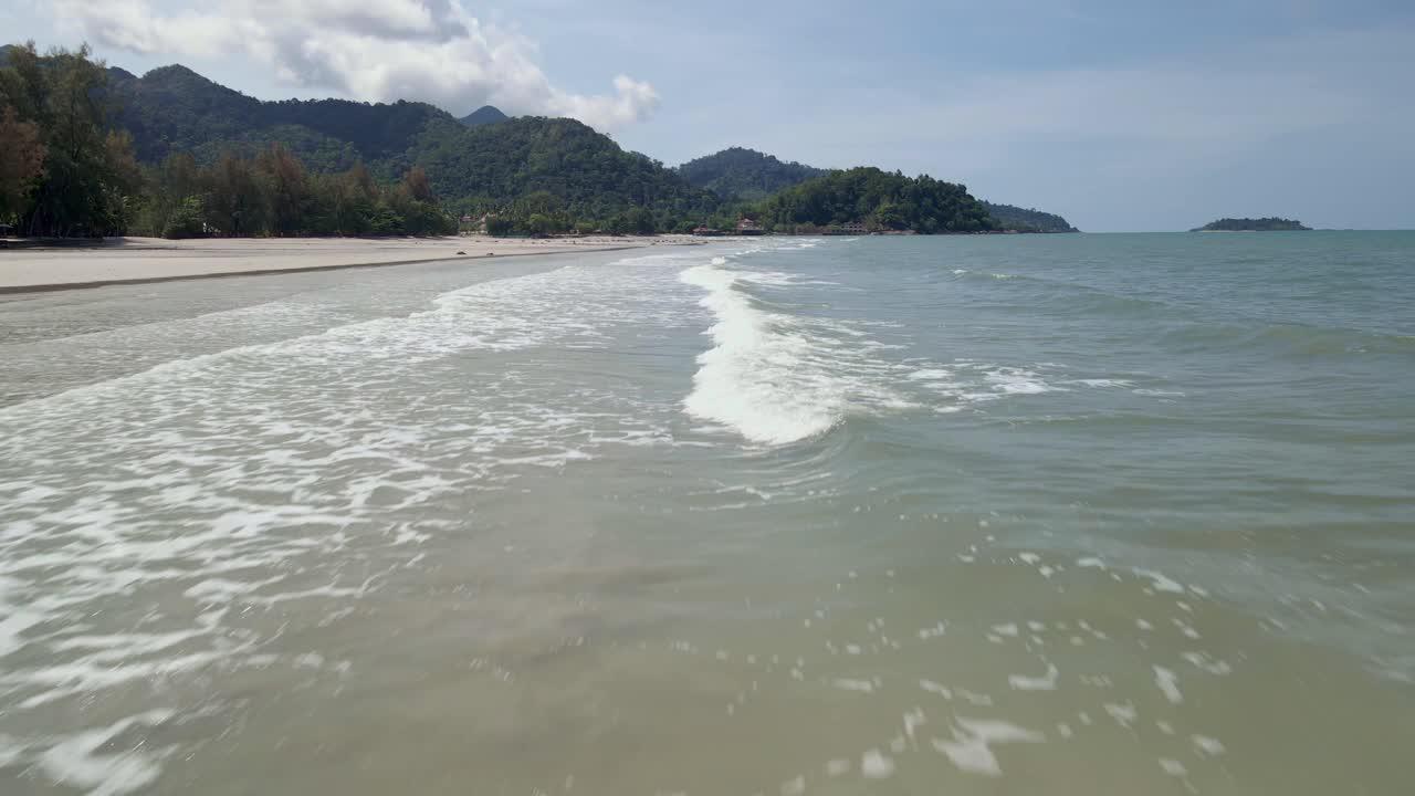 카메라는 작은 파도, 해변, 해안선과 함께 열대 해변을 따라 빠른 속도로 날아갑니다.