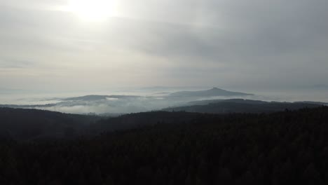 aerial shot of the iconic mount pico sacro, located near santiago de compostela, galicia. the video captures the landscape on a morning with clouds in the sky and fog enveloping the hills.
