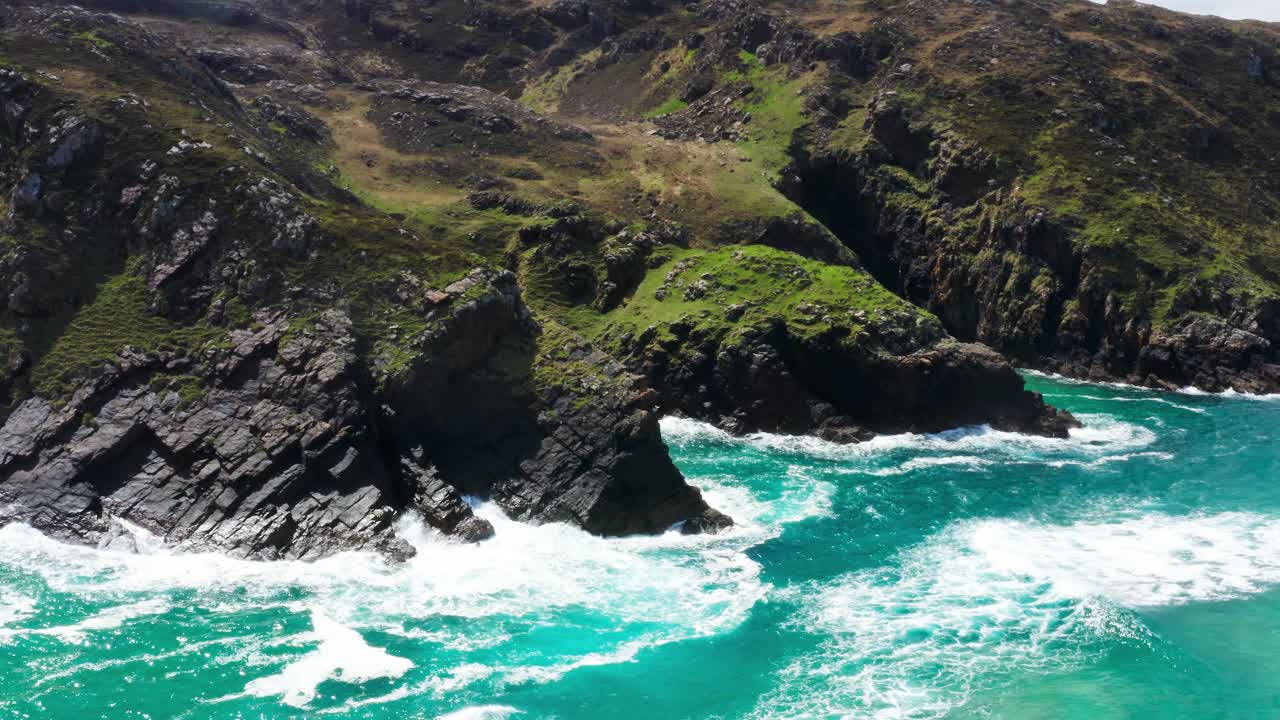 Aerial orbit over sea cliffs beside Murder Hole Beach, Donegal, with turquoise water and dramatic rocky coastline
