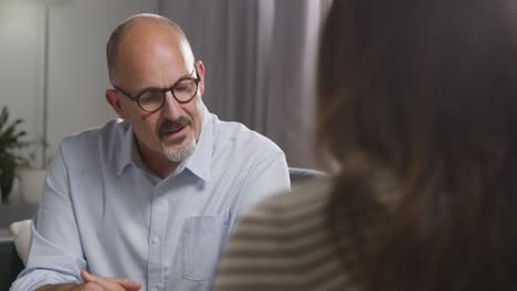 mature man sitting on sofa talking with female counsellor about general or mental health issue 7