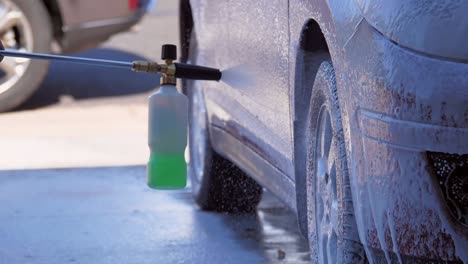 a car is spray washed by hand with cleaning liquid - slow motion footage