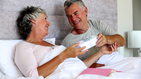 Husband-giving-a-gift-to-his-wife-while-she-is-reading-a-book