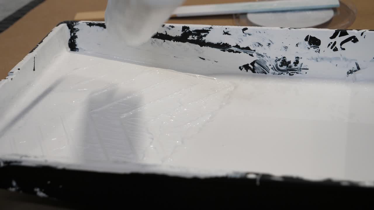 Verfroller in verfbakje close-up - Witte grondverf in zwart plastic bakje