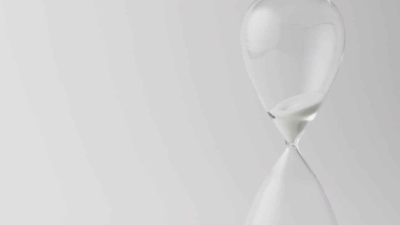 Video of hourglass with sand pouring, copy space on white background