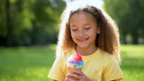 a young girl enjoying a colorful snow cone in a sunny park