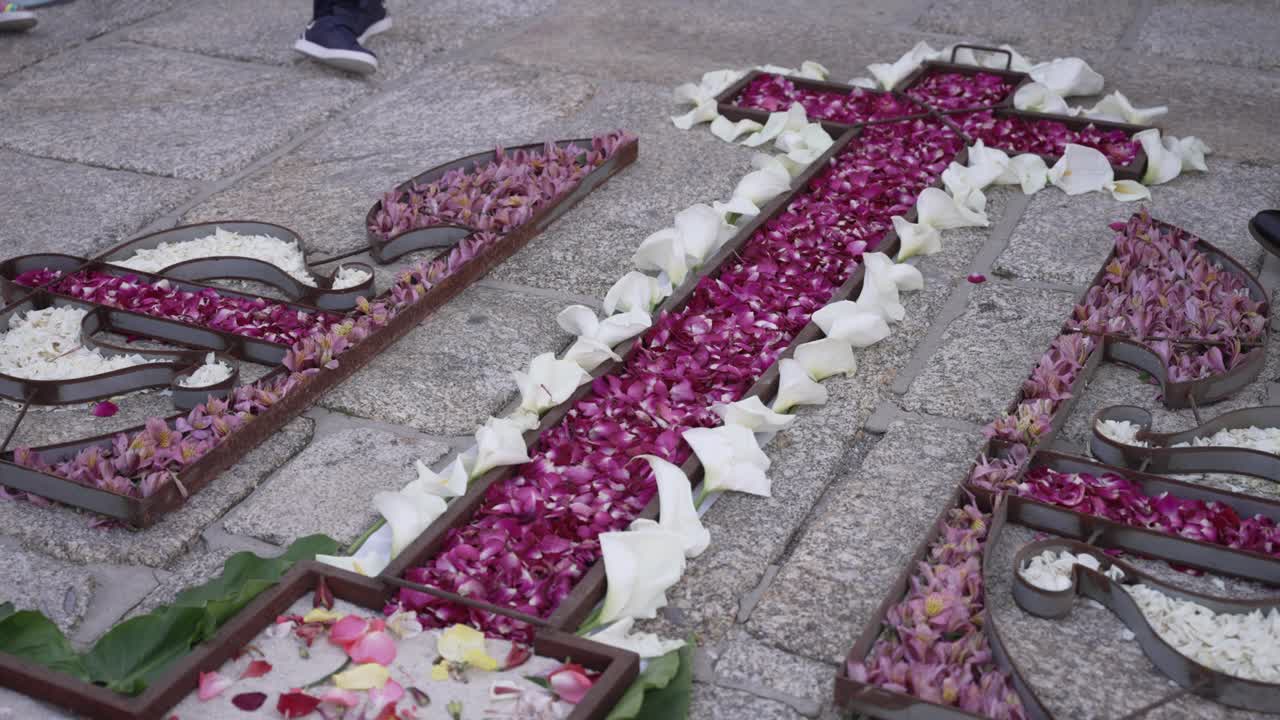 colorful floral cross laid on stone pavement for festival