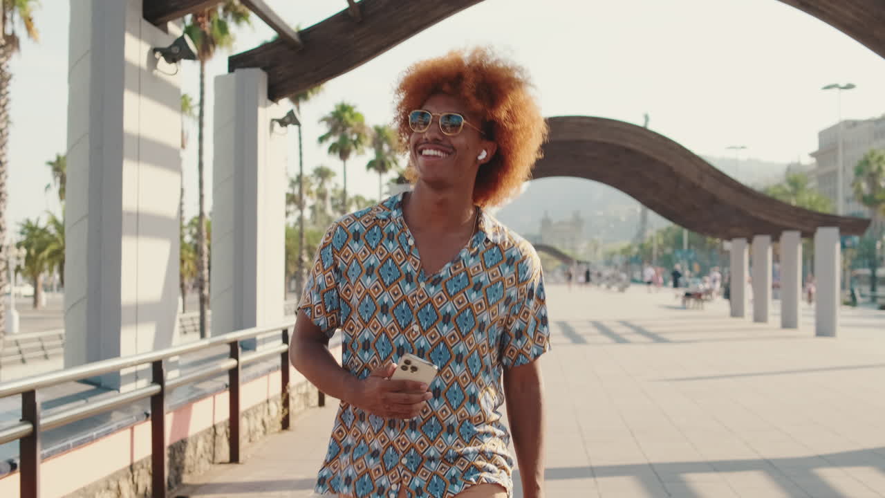 Happy Young Man with Curly Hair Walking and Listening to Music