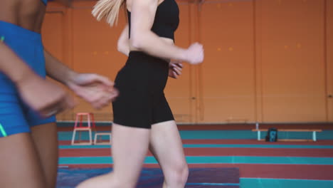 close up of two multiethnic female athletes running together on an indoor track