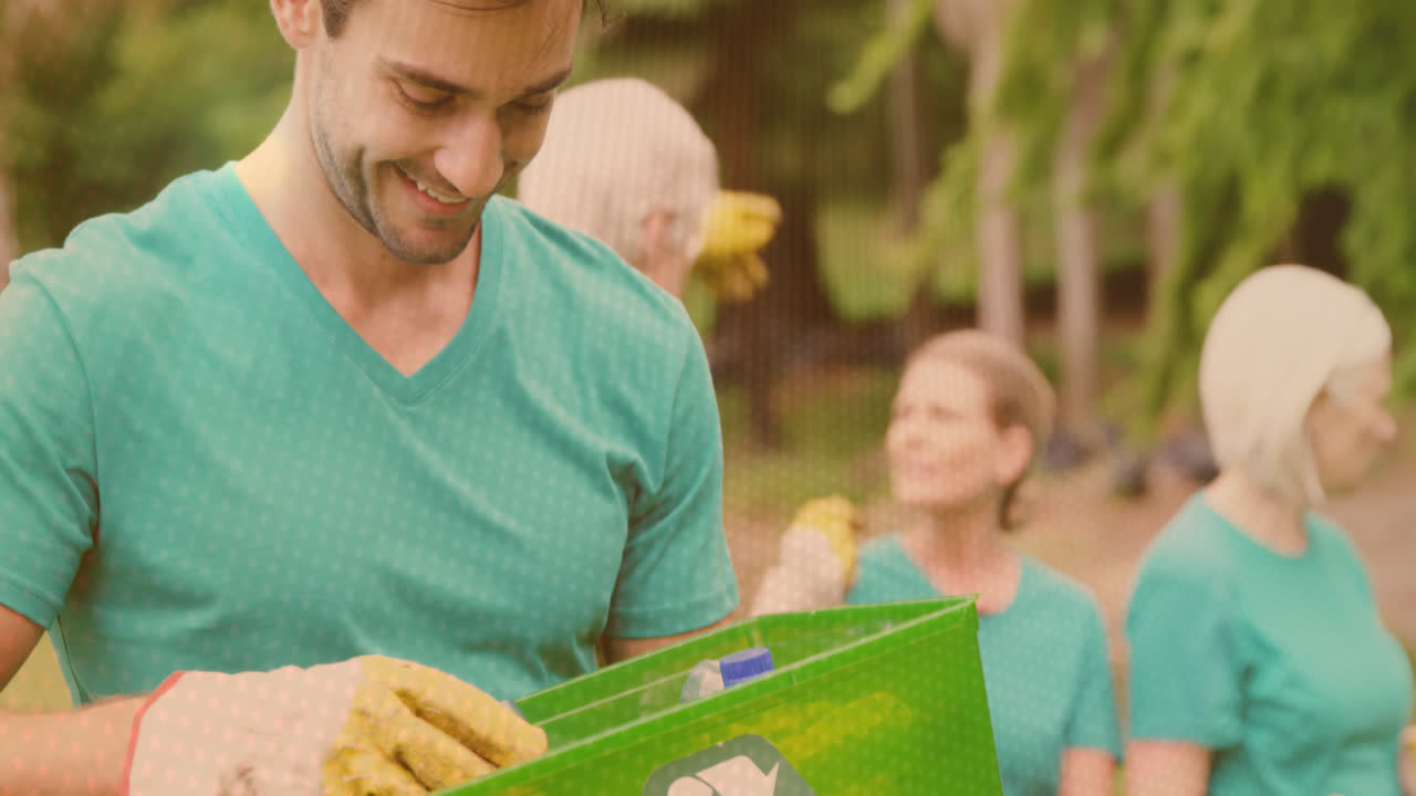 video de luces sobre un hombre caucásico feliz reciclando con voluntarios en el campo