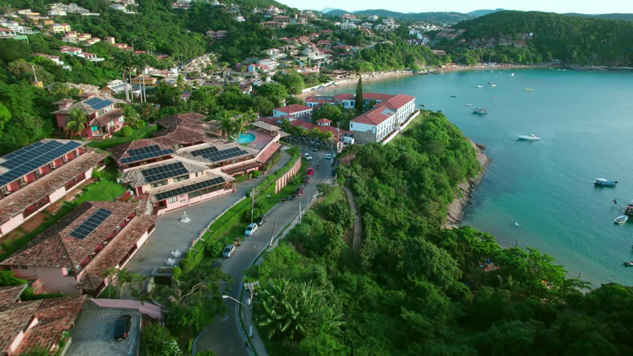 Tilt up aerial view of tourist villas with solar panels on their tiled roofs on the shores of Joao Fernandes Beach, B&uacute;zios, Brazil